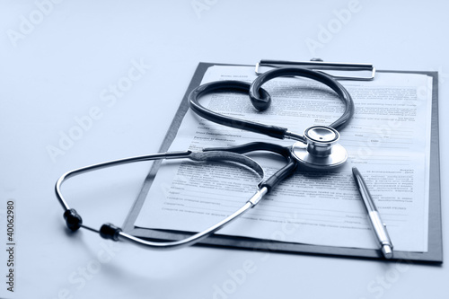 A stethoscope, a pen on a clipboard, isolated on white