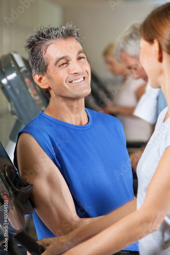 Trainer lacht Frau im Fitnesscenter an