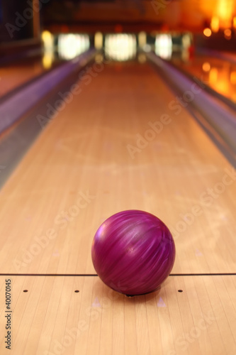 violet sphere ball standing on long bowling lane before strike