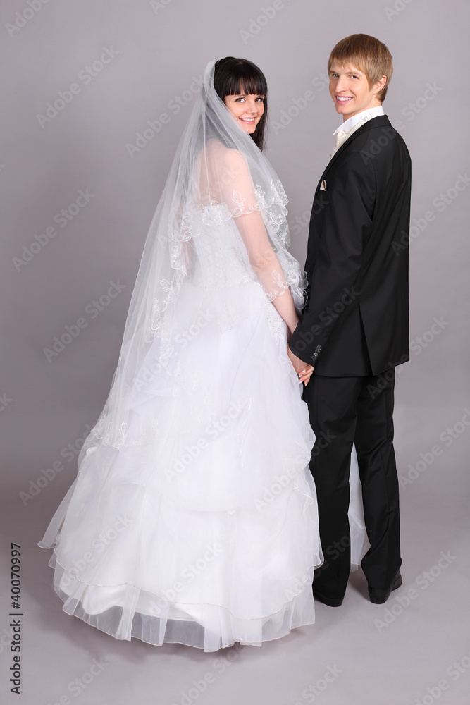 Groom and beautiful bride turned and look into camera in studio Groom and beautiful bride turned and look into camera in studio