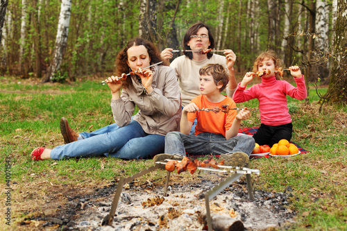 Mother, father and children eat grilled shish kebab outdoor