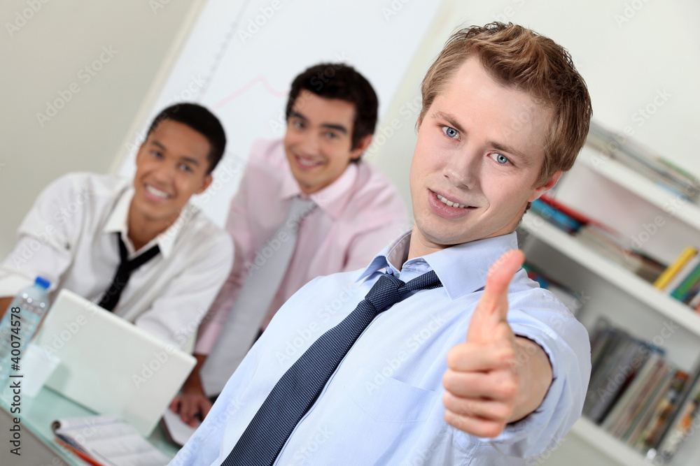 Young businessman giving thumbs-up during meeting Young businessman giving thumbs-up during meeting