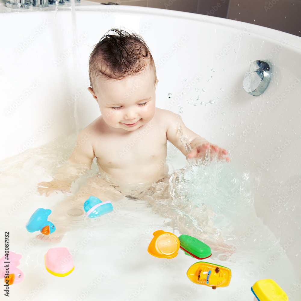 Cute smiling baby splashing water while taking a bath Cute smiling baby splashing water while taking a bath