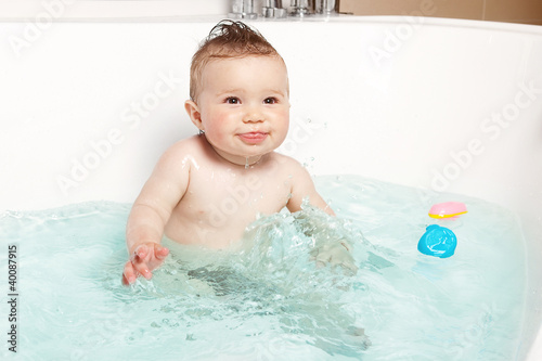 Cute baby having fun and smiling while taking a bath