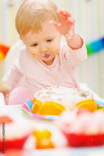 Eat smeared baby having fun with birthday cake