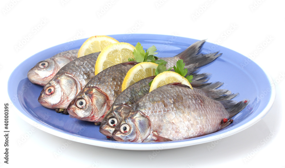 Fresh fishes with lemon and parsley on plate isolated on white Fresh fishes with lemon and parsley on plate isolated on white