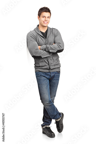 Tableau sur toile Full length portrait of a happy young man leaning against wall
