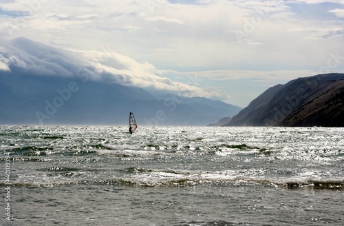 Windsurfer on a sea with mountains and clouds