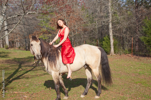 Woman in a red dress, riding a horse bareback