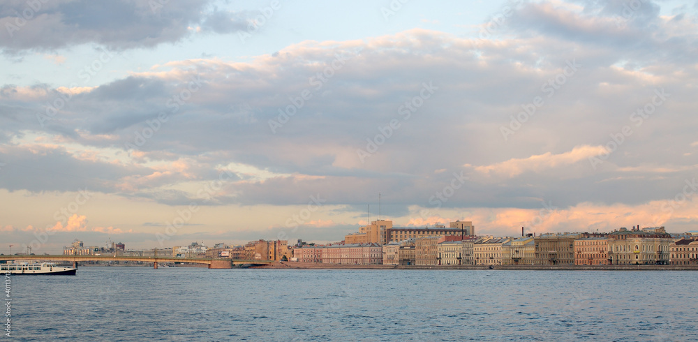 Picturesque city landscape with a cloudy sky, river, ship, and h