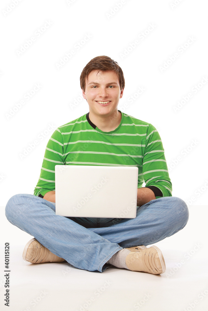 A young man sitting on the floor with a laptop