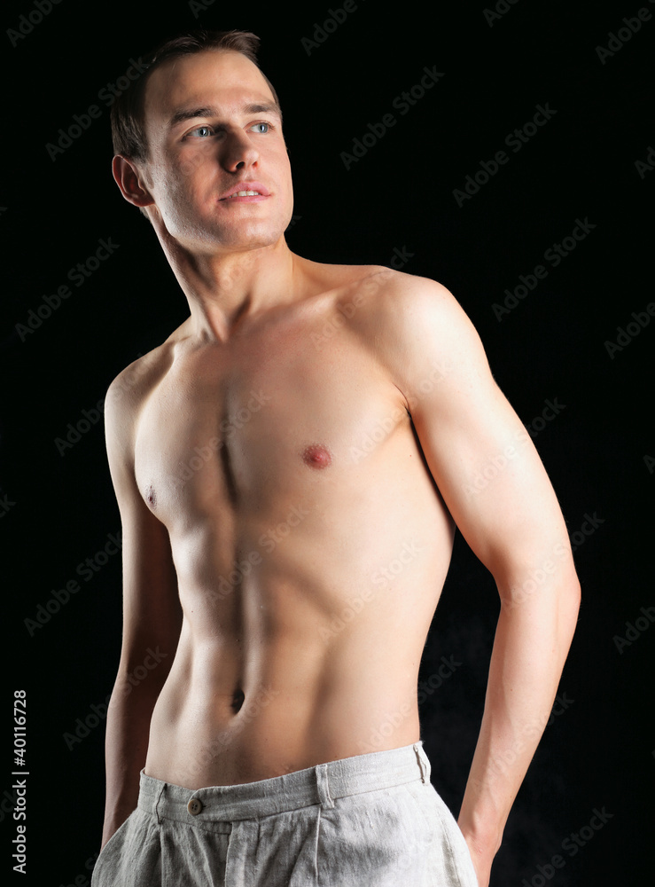 Fototapeta premium Portrait of a naked muscular man, isolated on black background