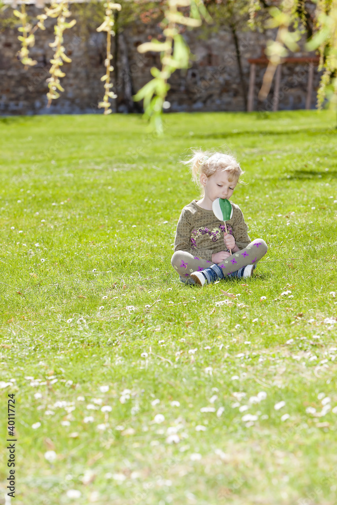 little girl with a lollipop sitting on grass little girl with a lollipop sitting on grass