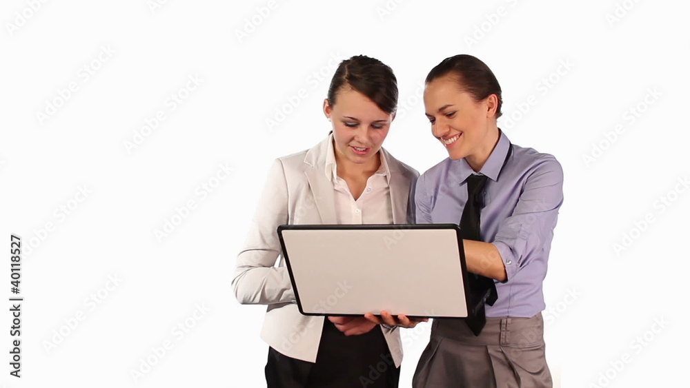 Two businesswomen laughing in front of the laptop, isolated Two businesswomen laughing in front of the laptop, isolated