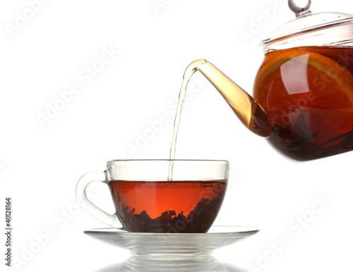 Glass teapot pouring black tea into cup isolated on white