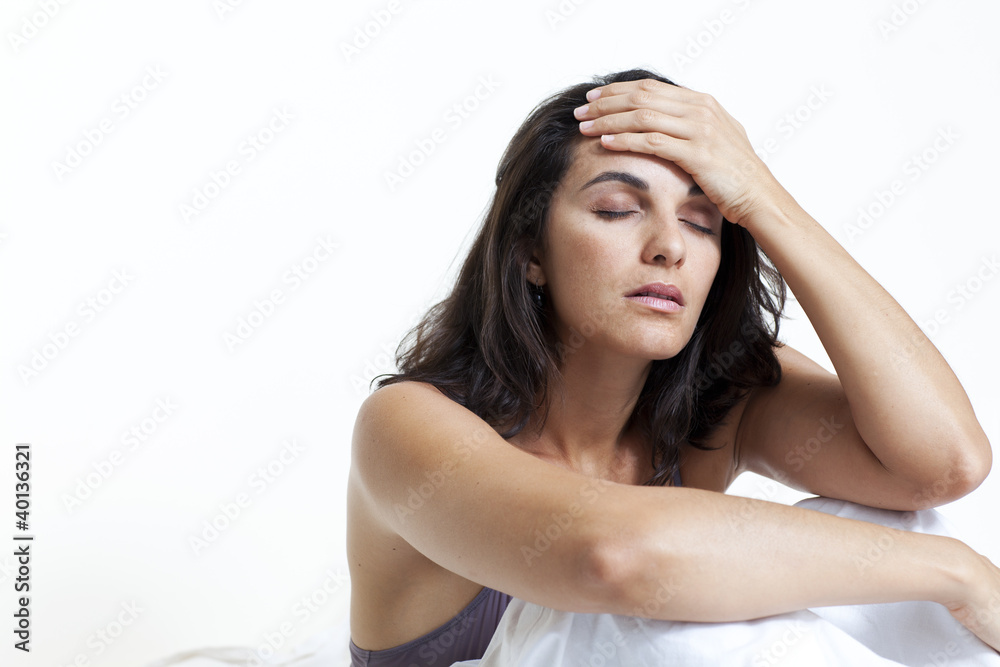 Schöne Frau mit Kopfschmerzen im Bett sitzend Schöne Frau mit Kopfschmerzen im Bett sitzend