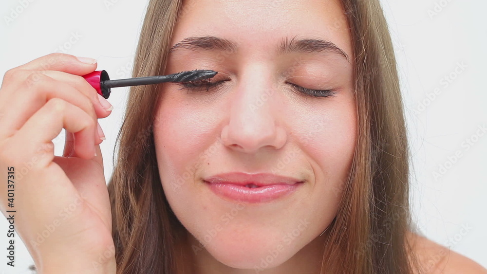 Joyful brunette applying mascara on her eyelashes Joyful brunette applying mascara on her eyelashes