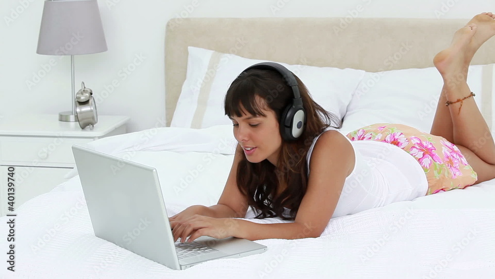 Smiling woman using a laptop while wearing headphones