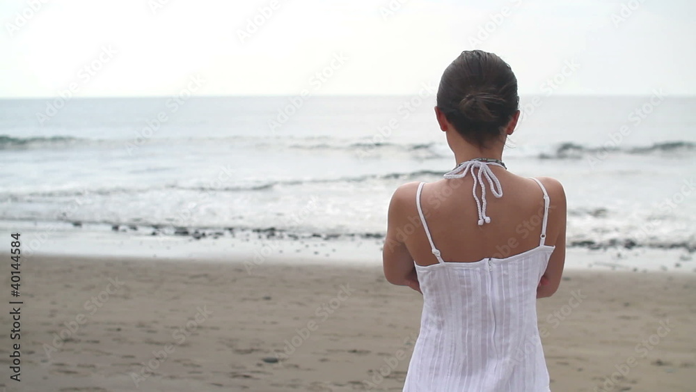 Lonely woman standing at the beach and looking at sea Lonely woman standing at the beach and looking at sea