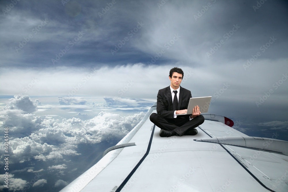 Fototapeta premium Businessman sat on the wing of an airplane