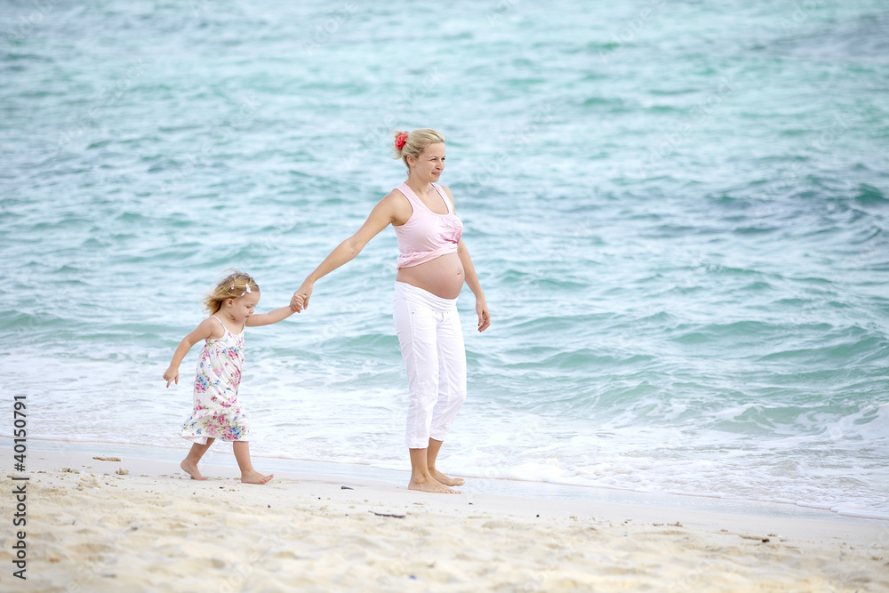 junge schwangere mutter mit ihrer tochter am strand junge schwangere mutter mit ihrer tochter am strand