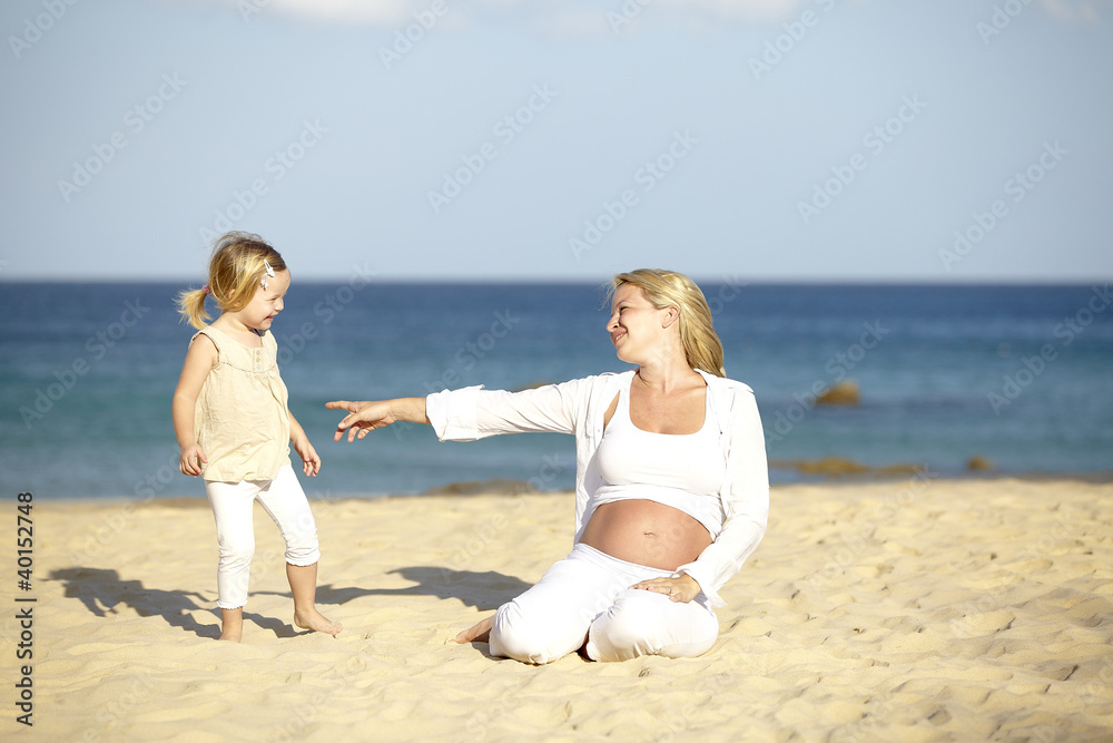 junge schwangere mutter mit ihrer tochter am strand junge schwangere mutter mit ihrer tochter am strand