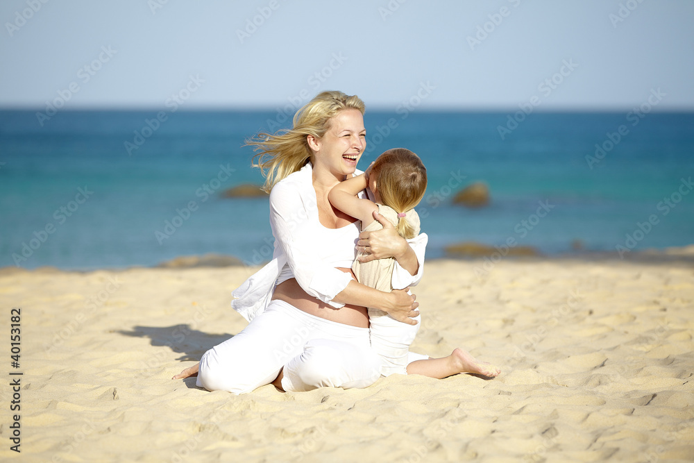 junge schwangere mutter mit ihrer tochter am strand junge schwangere mutter mit ihrer tochter am strand