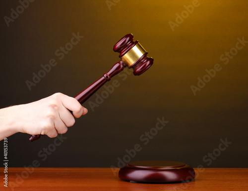 Judge's gavel in hand on brown background photo