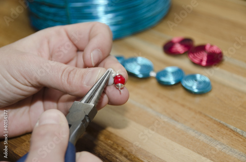 mains de femme créant un bijou de mode