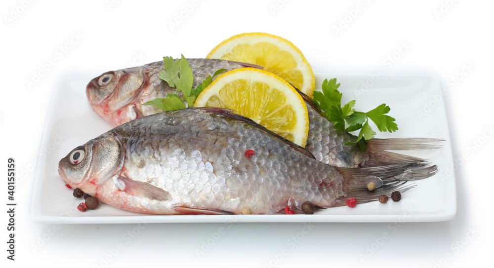 Fresh fishes with lemon and parsley on plate isolated on white Fresh fishes with lemon and parsley on plate isolated on white