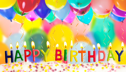 Happy birthday lit candles on colorful balloons background