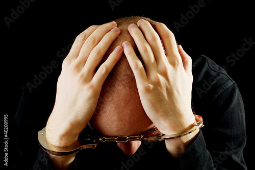 Foto Repentant bandit in handcuffs isolated on black