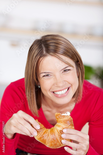 lachende frau isst ein croissant