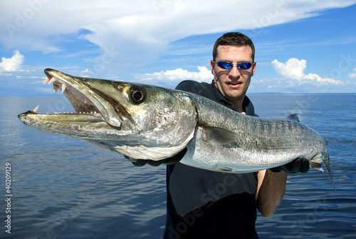 Happy fisherman holding a giant barracuda