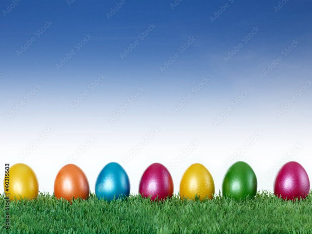 Happy Easter! Colourful eggs in the meadow with blue sky