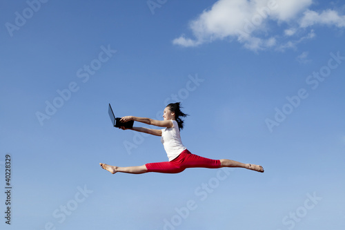 Beautiful woman jumps with laptop