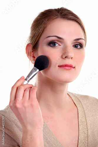 Beautiful young woman applying powder with makeup brush