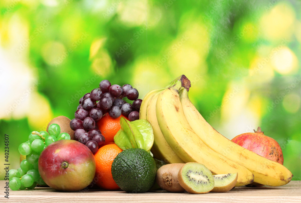 Assortment of exotic fruits on wooden table on green background Assortment of exotic fruits on wooden table on green background