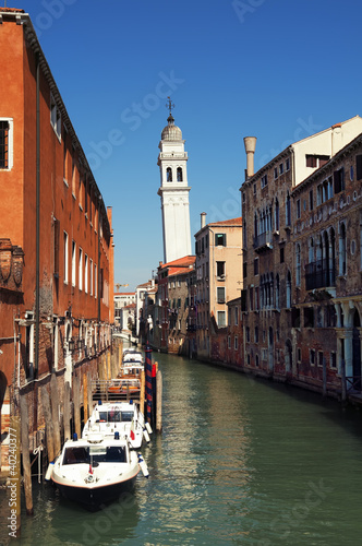 Canal with a leaning bell tower in Venice.