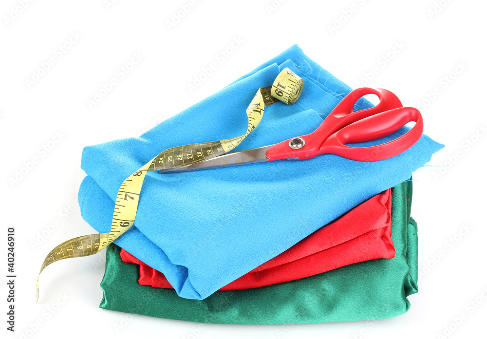 Naklejka premium Scissors and measuring tape on fabric isolated on white