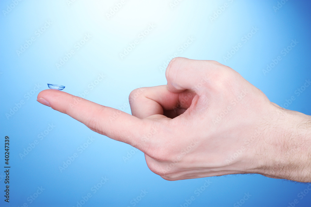 contact lens on finger on blue background