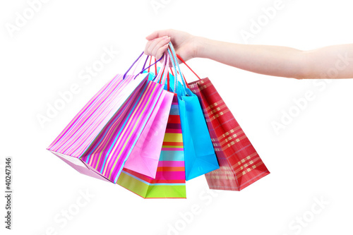 Female hand holding bright shopping bags isolated on white