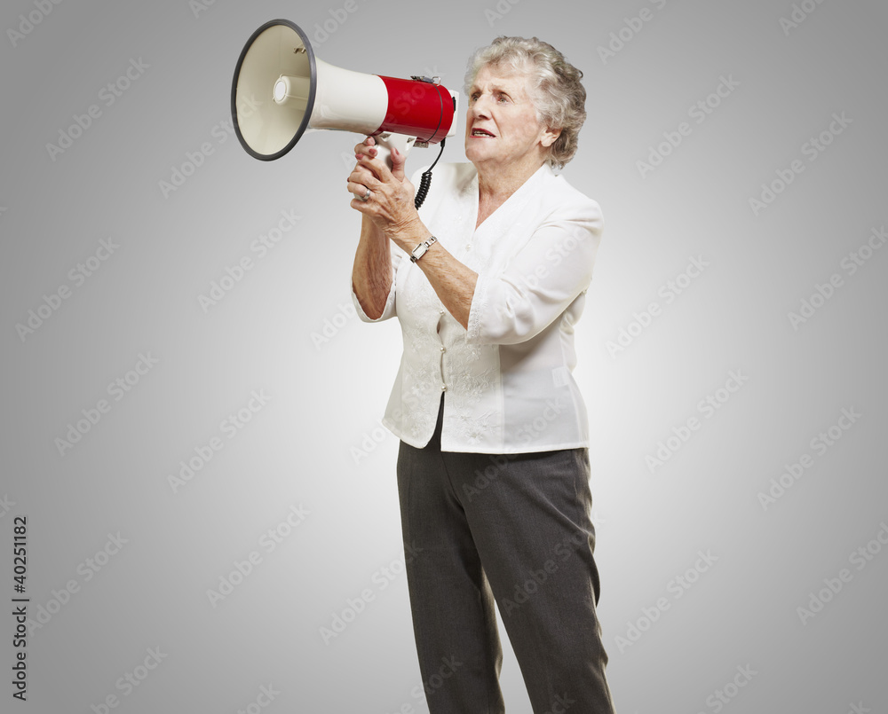 portrait of senior woman holding megaphone over grey background portrait of senior woman holding megaphone over grey background