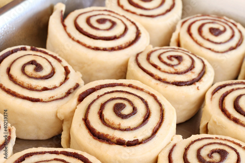 Raw cinnamon buns ready to bake with selective focus.