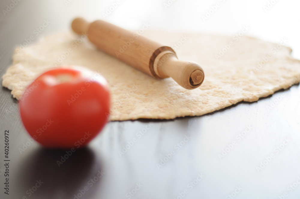 Sfoglia di pasta integrale per pizza con mattarello e pomodoro Sfoglia di pasta integrale per pizza con mattarello e pomodoro