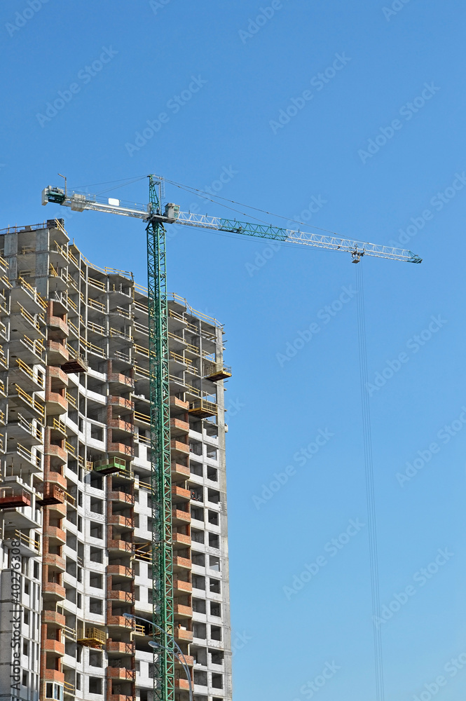 Building crane and building under construction against blue sky Building crane and building under construction against blue sky