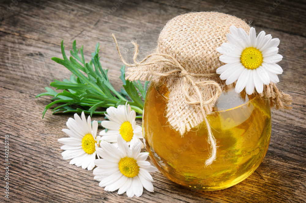 Glass pot of honey with daisies