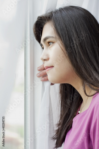 Side profile of teen girl looking out window