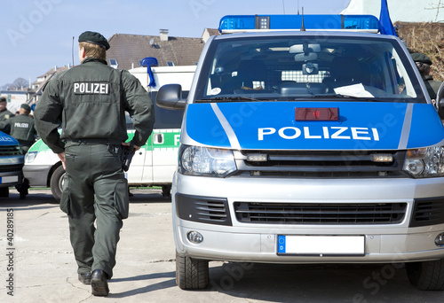 Polizist neben Einsatzwagen