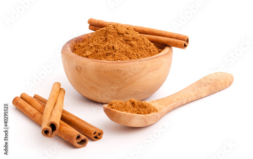 powder of cinnamon in wooden bowl with spoon and.Cinnamon sticks photo